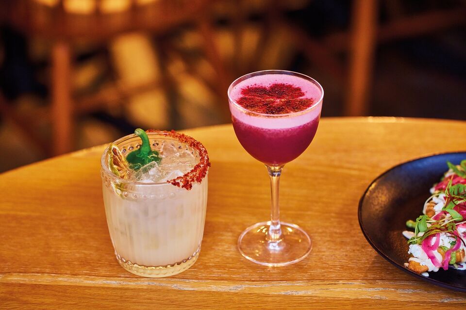 A margarita mocktail and a pink berry mocktail on a table