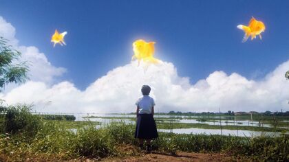 Still from short film there are new suns. a girl looks over paddy fields and in the sky above there are 3 large goldfish