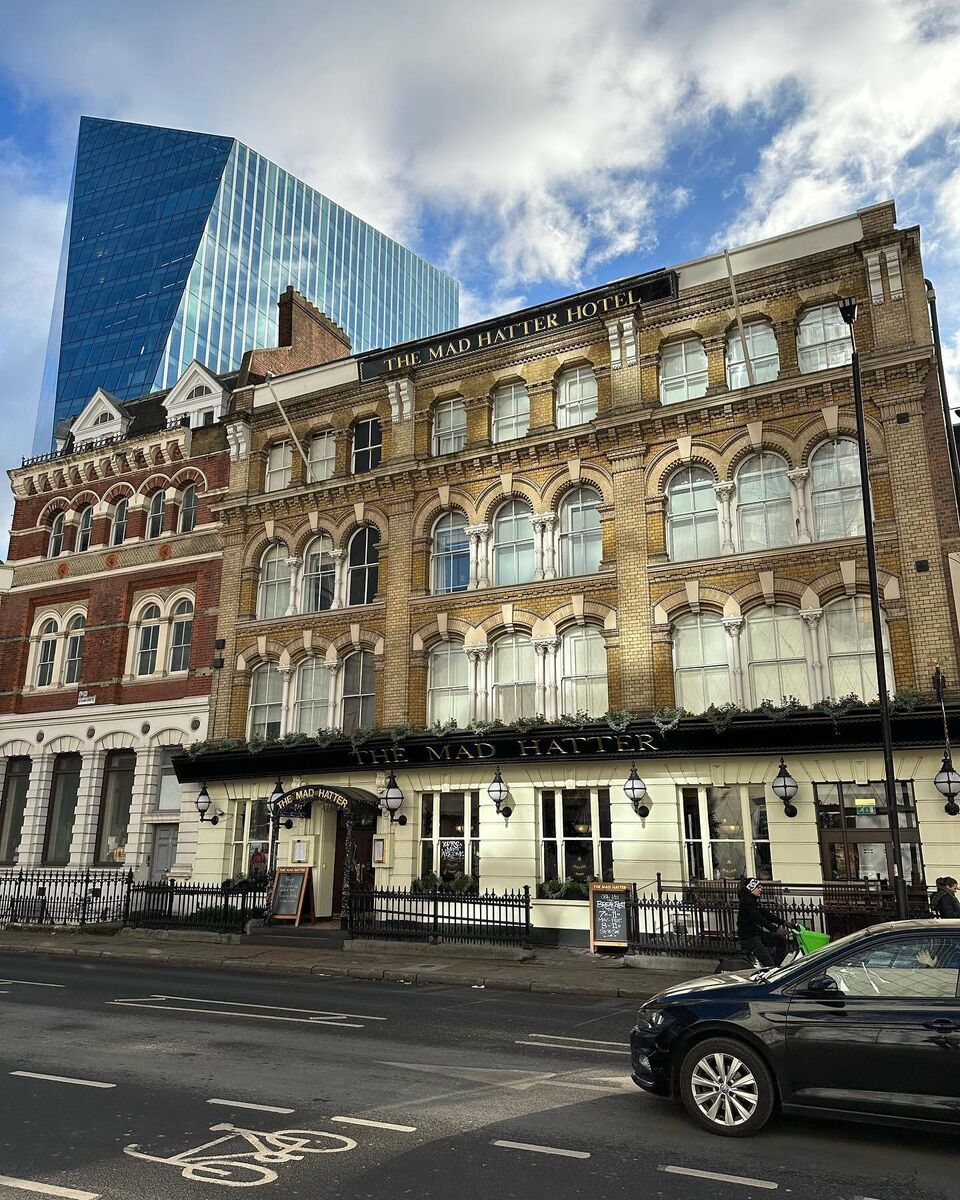 view of the whole mad hatter hotel building from the street with a car passing in front