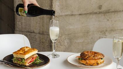 close up view of table with two plates of sandwiches and a glass of champagne being poured