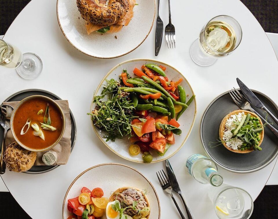 aerial view of a cafe table with 4 dishes includes salad, soup, a angel and a tart