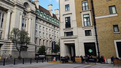 view of people sitting at the starbucks coffee shop terrace, with edwardian facade of the county hall building in the background