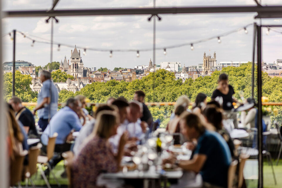 diners out of focus in foreground at the oxo tower restaurant with treeline viewed over the river in focus in the background