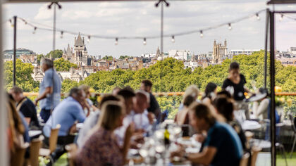 diners out of focus in foreground at the oxo tower restaurant with treeline viewed over the river in focus in the background