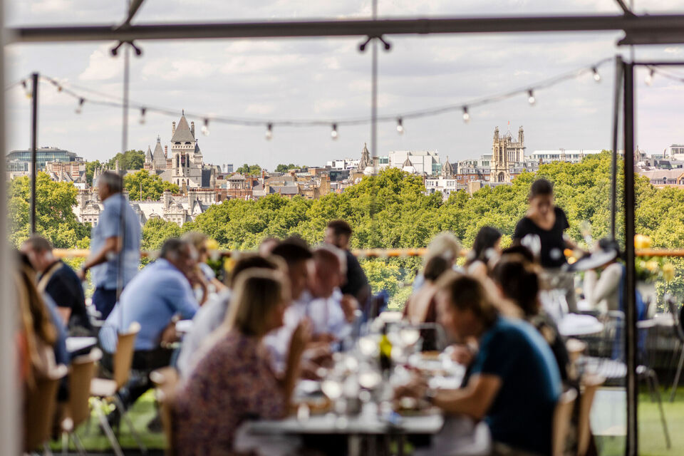 diners out of focus in foreground at the oxo tower restaurant with treeline viewed over the river in focus in the background
