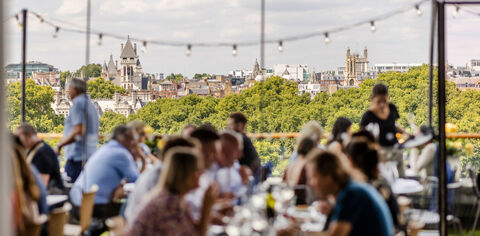 diners out of focus in foreground at the oxo tower restaurant with treeline viewed over the river in focus in the background