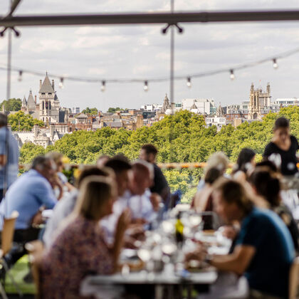diners out of focus in foreground at the oxo tower restaurant with treeline viewed over the river in focus in the background