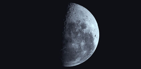 Close up image of the moon in a black sky with the left side of the moon obscured in shadows
