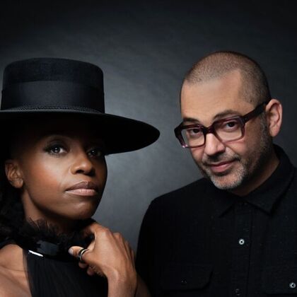 Two members of Morcheeba against a black background wearing black clothes, one person in a hat.
