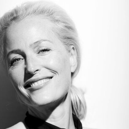 Gillian Anderson wears a black dress in a black and white photo