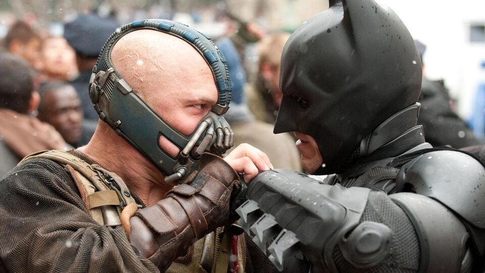 Batman characters Bane and the Batman lock fists and face each other with a look of malice in each characters eyes