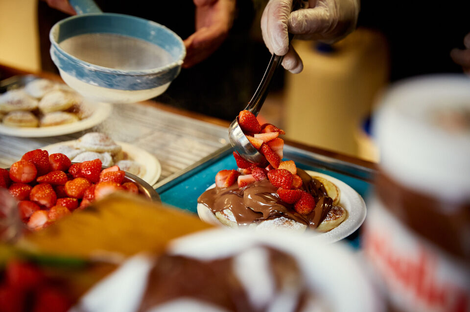 Dutch pancakes being prepared topped with nutella and strawberries