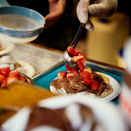 Dutch pancakes being prepared topped with nutella and strawberries