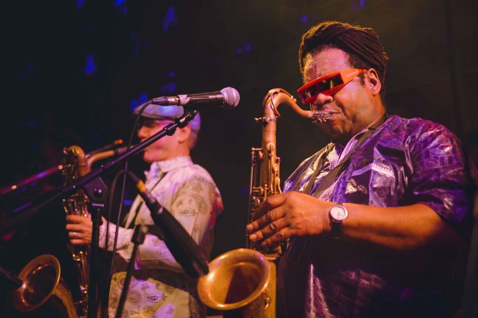 Two performers playing trumpets wearing jazzy suits