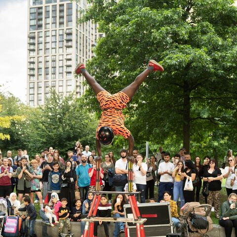 A street acrobat performs in front of Jubilee Gardens