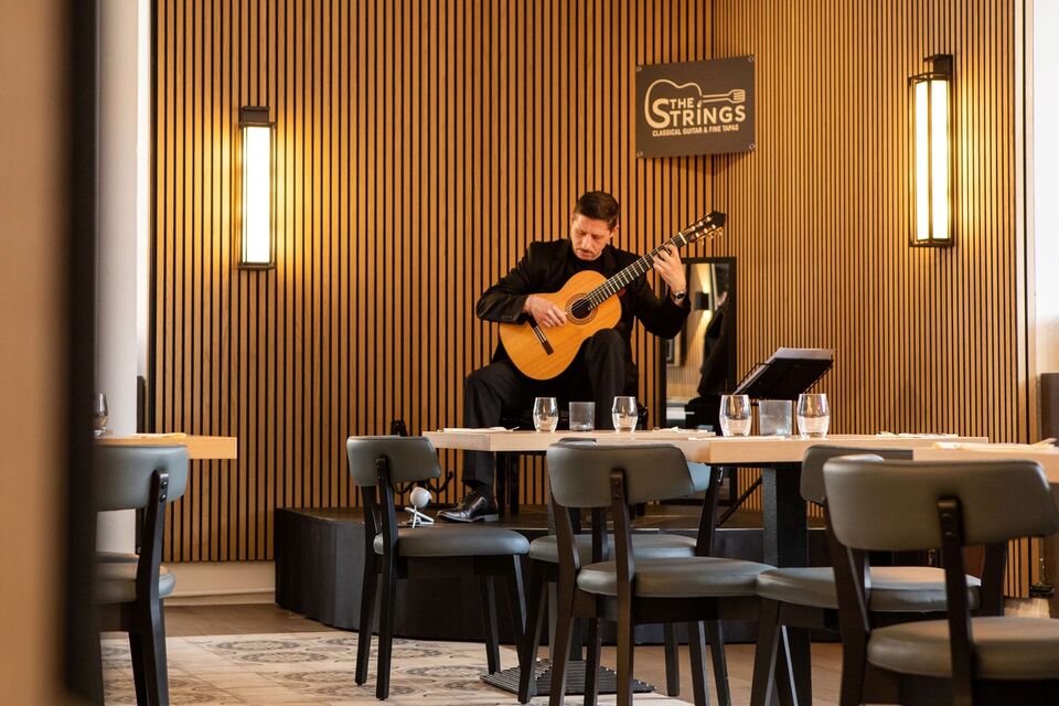 Santy Masciaro playing classical guitar at his restaurant The Strings