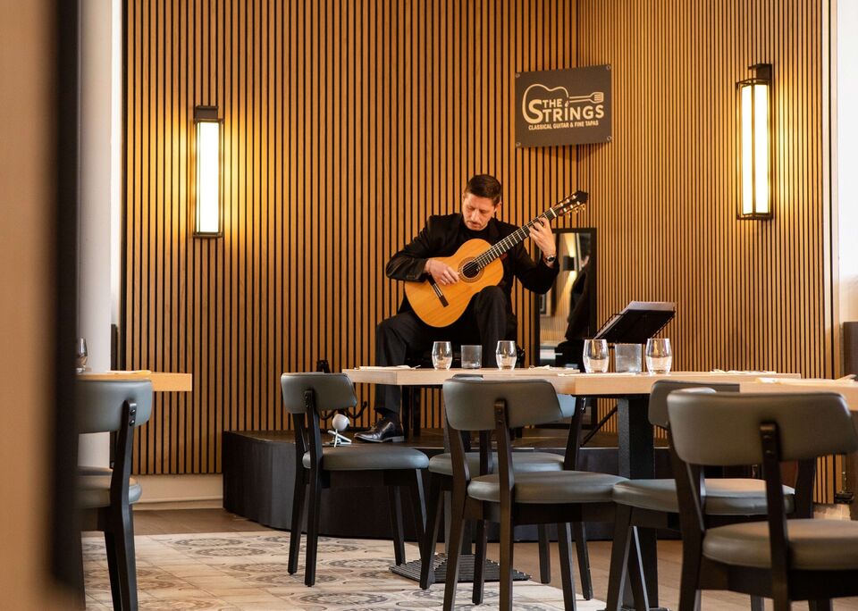 Santy Masciaro playing classical guitar at his restaurant The Strings